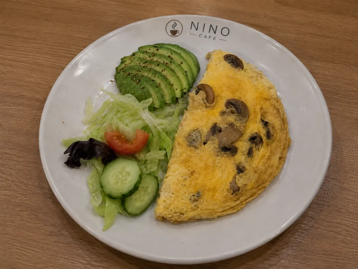 Mushroom omelette on a Nino Cafe plate with side salad and sliced avocado