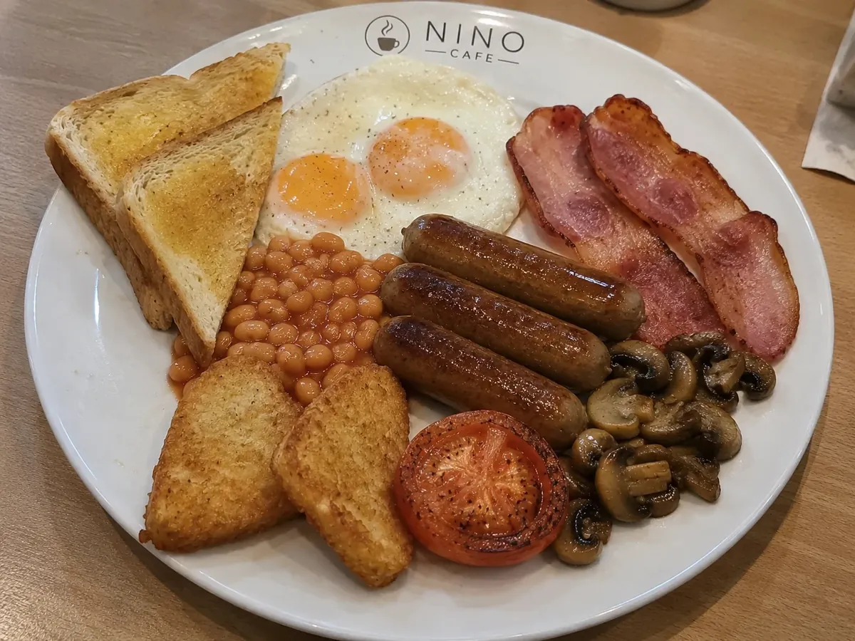 The Mega breakfast on a Nino Cafe plate — eggs, beef sausages, turkey bacon, hash browns, beans, grilled tomato, mushrooms and toast